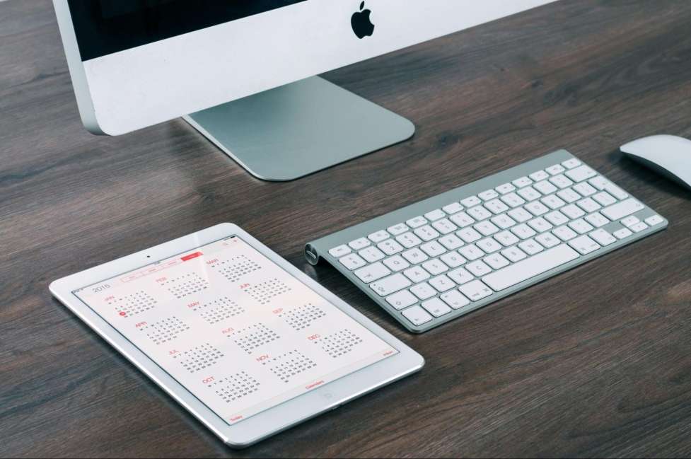 stock image of a computer and a calendar on a desk 