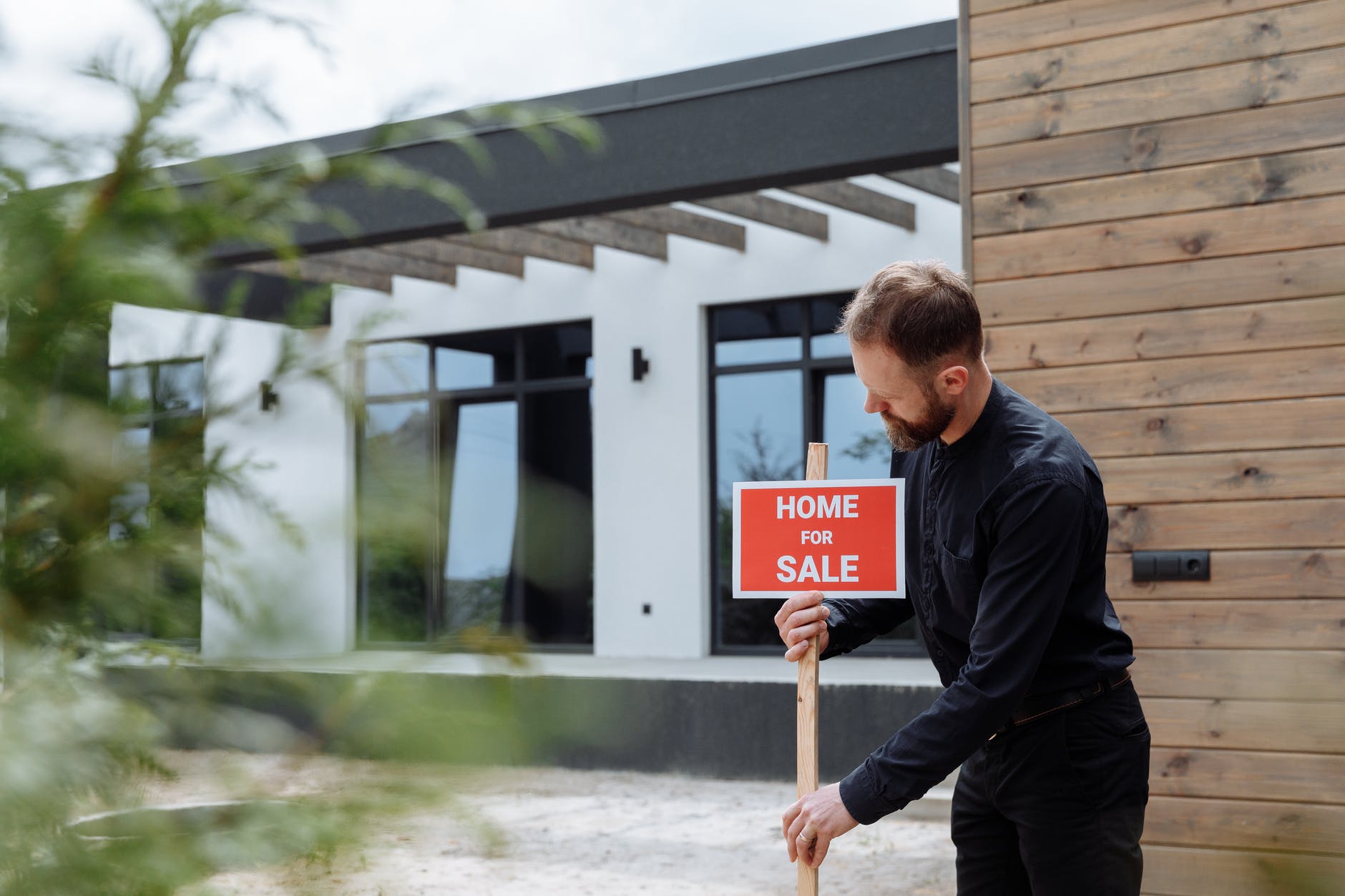 a man in black long sleeves putting the signage outside a house