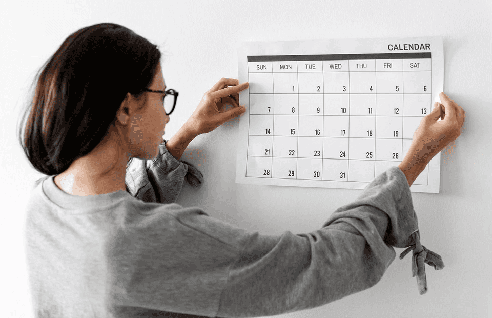 stock image of a woman looking to a wall calendar 